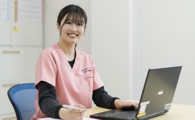ピンクのユニフォームを着たスタッフがパソコンで業務を行っている